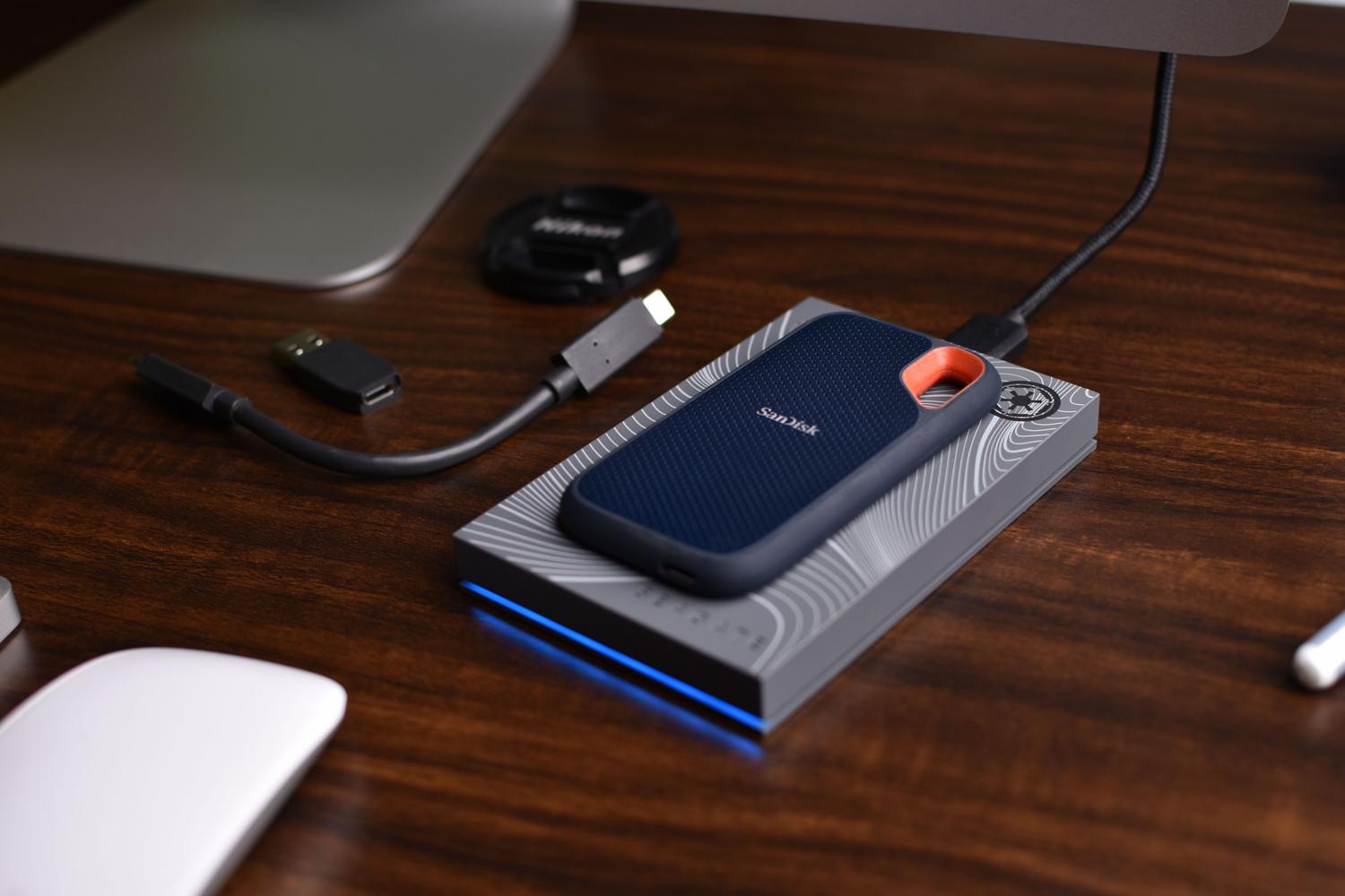 محرك أقراص SSD محمول وملحقات USB على جهاز كمبيوتر مكتبي احترافي، مما يدل على أهمية النسخ الاحتياطي واستخدام وحدات تخزين قوية.